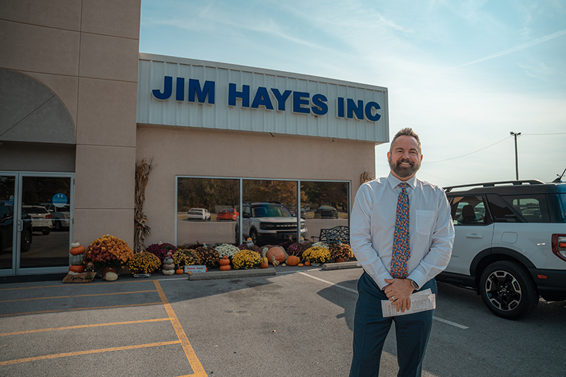 Jamie Hayes stands in front of the Jim Hayes, Inc. car dealership in Harrisburg, Illinois.