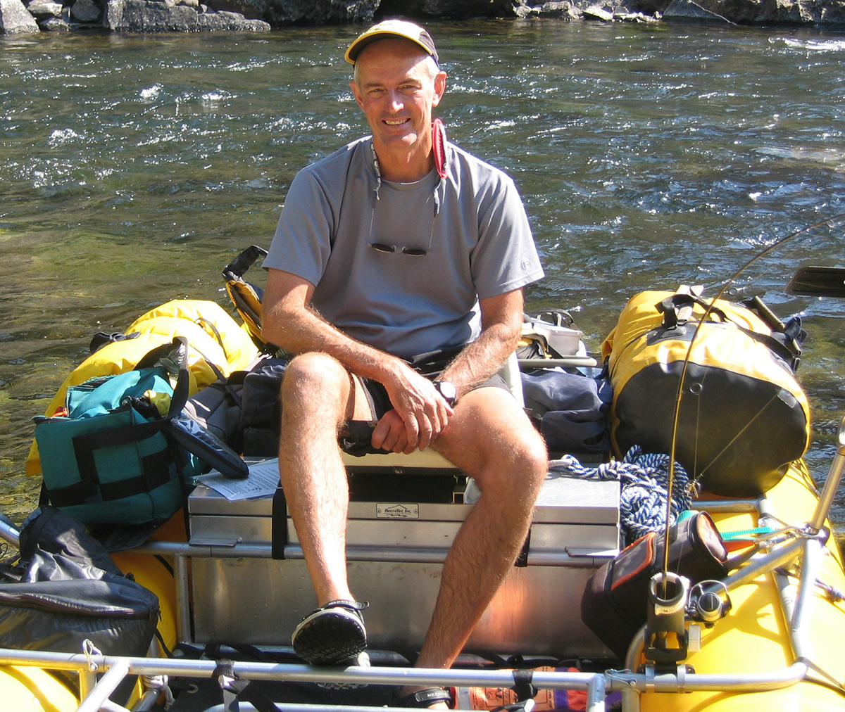 Chuck Trover sitting on rafter in a river.
