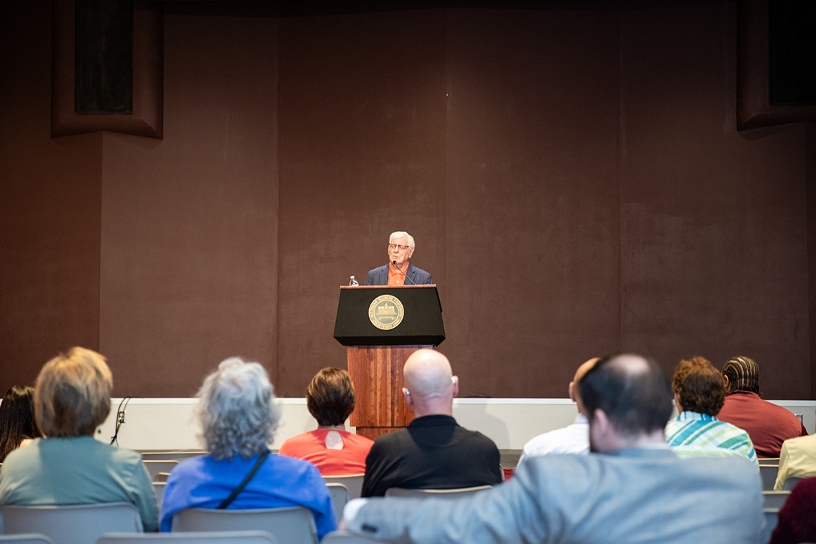 Glenn Poshard stands at a podium in SIU’s Student Center ballrooms, reading poetry to an audience seated in rows. The event raised funds and food donations for the Saluki Food Pantry.