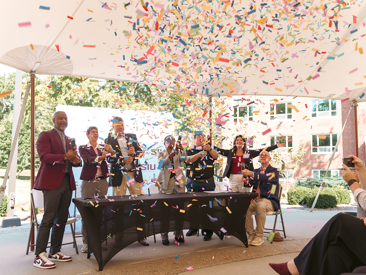 SIU Chancellor Austin Lane joins leaders from the SIU Foundation, SIU Alumni Association, SI Now, the City of Carbondale, Carbondale Main Street and the Carbondale Chamber of Commerce in celebrating the launch of Salukis Build Here with a burst of confetti following the signing ceremony on Wednesday, Oct. 1, 2025, at the Alumni Association Courtyard Tent outside Woody Hall. The partnership invites alumni to start, relocate or expand their businesses in Carbondale and Southern Illinois.