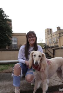 Lydia Phelps smiles next to a Saluki dog.