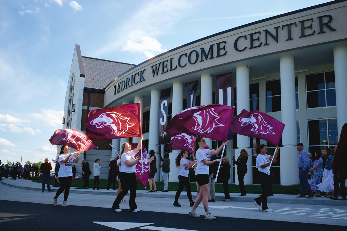 Marching Salukis wave the SIU flag in front of the Tedrick Welcome Center.