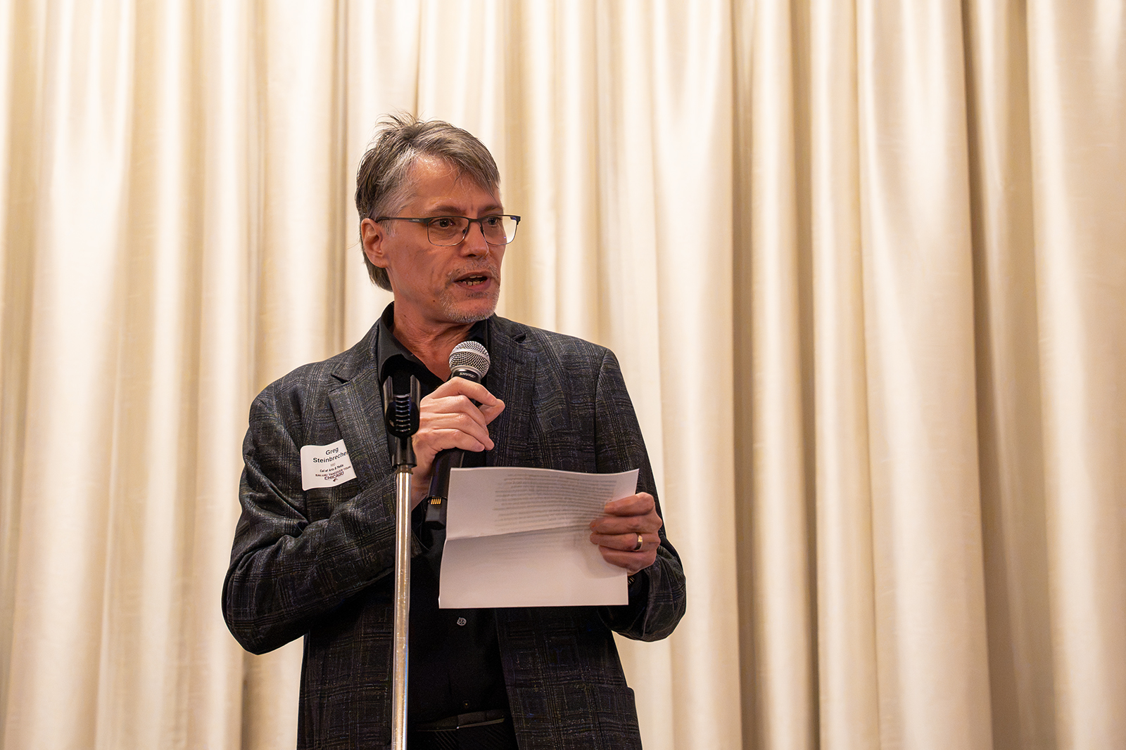 SIU alumnus Greg Steinbrecher speaks into a microphone while holding printed notes during the Saluki Takeover Tour Chancellor's Reception at the Palmer House in Chicago.